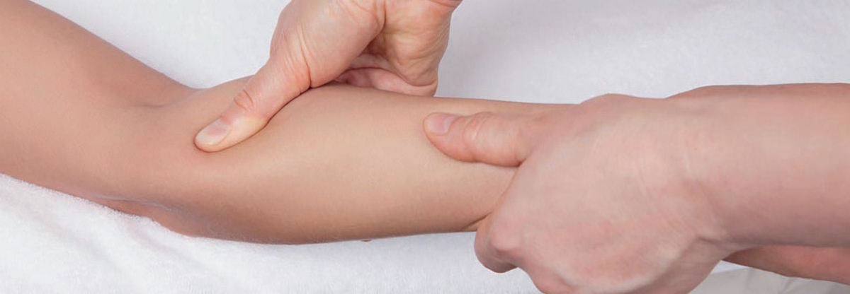 Der Therapeut drückt Faszienpunkte am Arm einer Patientin.