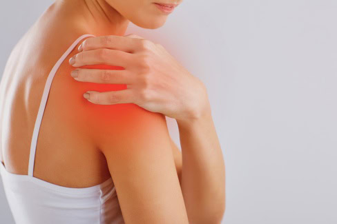 Frau mit Schulterschmerzen greift sich an die Schulter