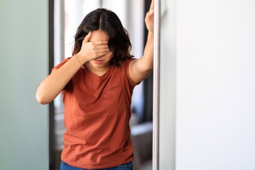 Schwindel – Ursachen, Symptome und häufige Erkrankungen im Überblick Frau mit starkem Schwindel hält sich an einem Türrahmen fest